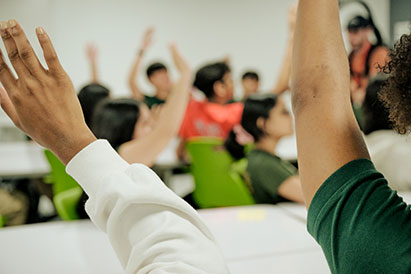 in the midst of students raising hands