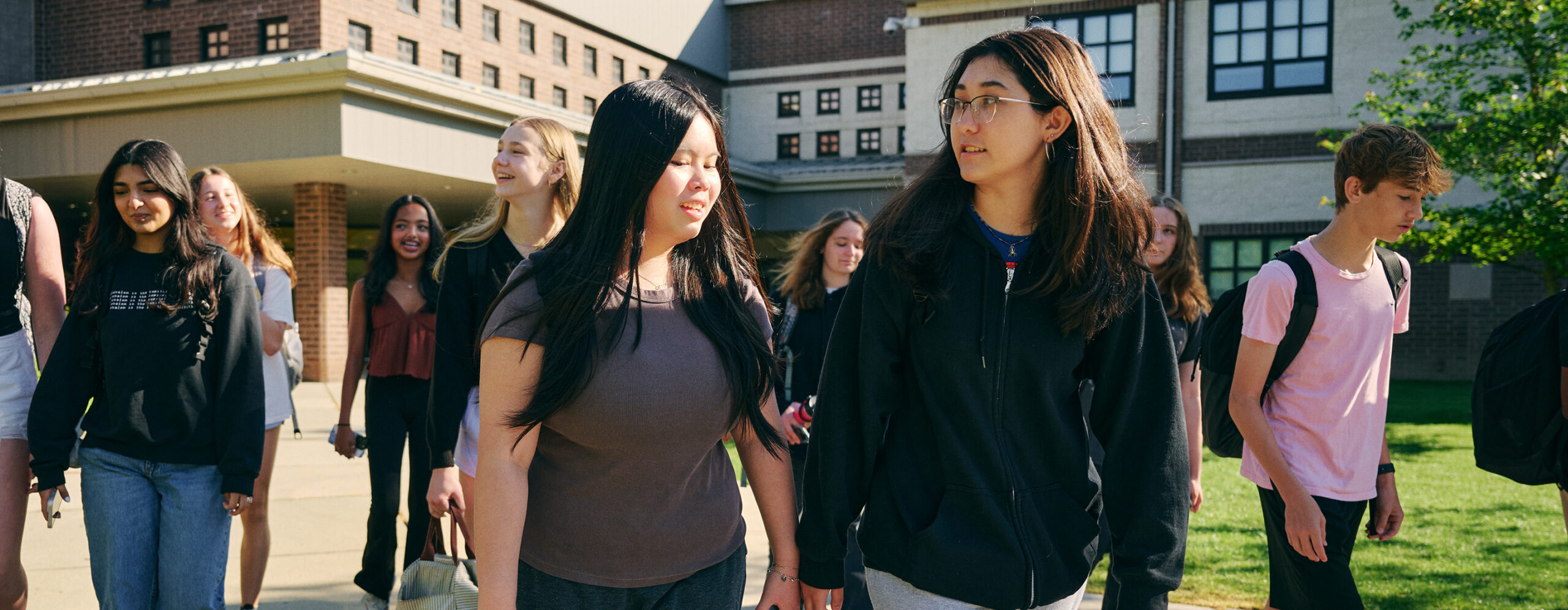 group of students walking and talking in front of school building