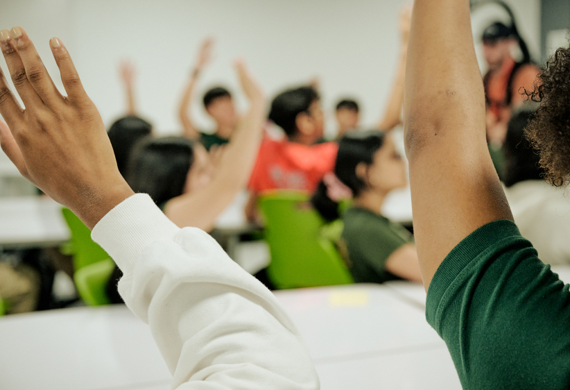 students raising their hands in a classroom setting