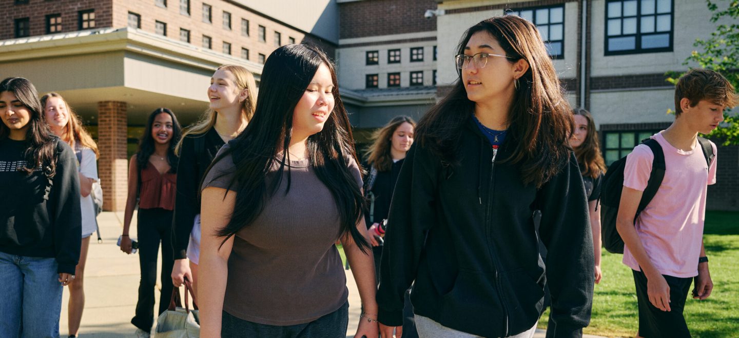 group of students walking and talking in front of school building